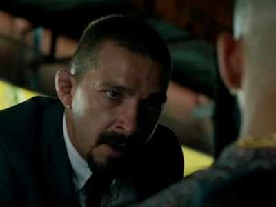 Shia LaBeouf is talking to another man and has an intense look.